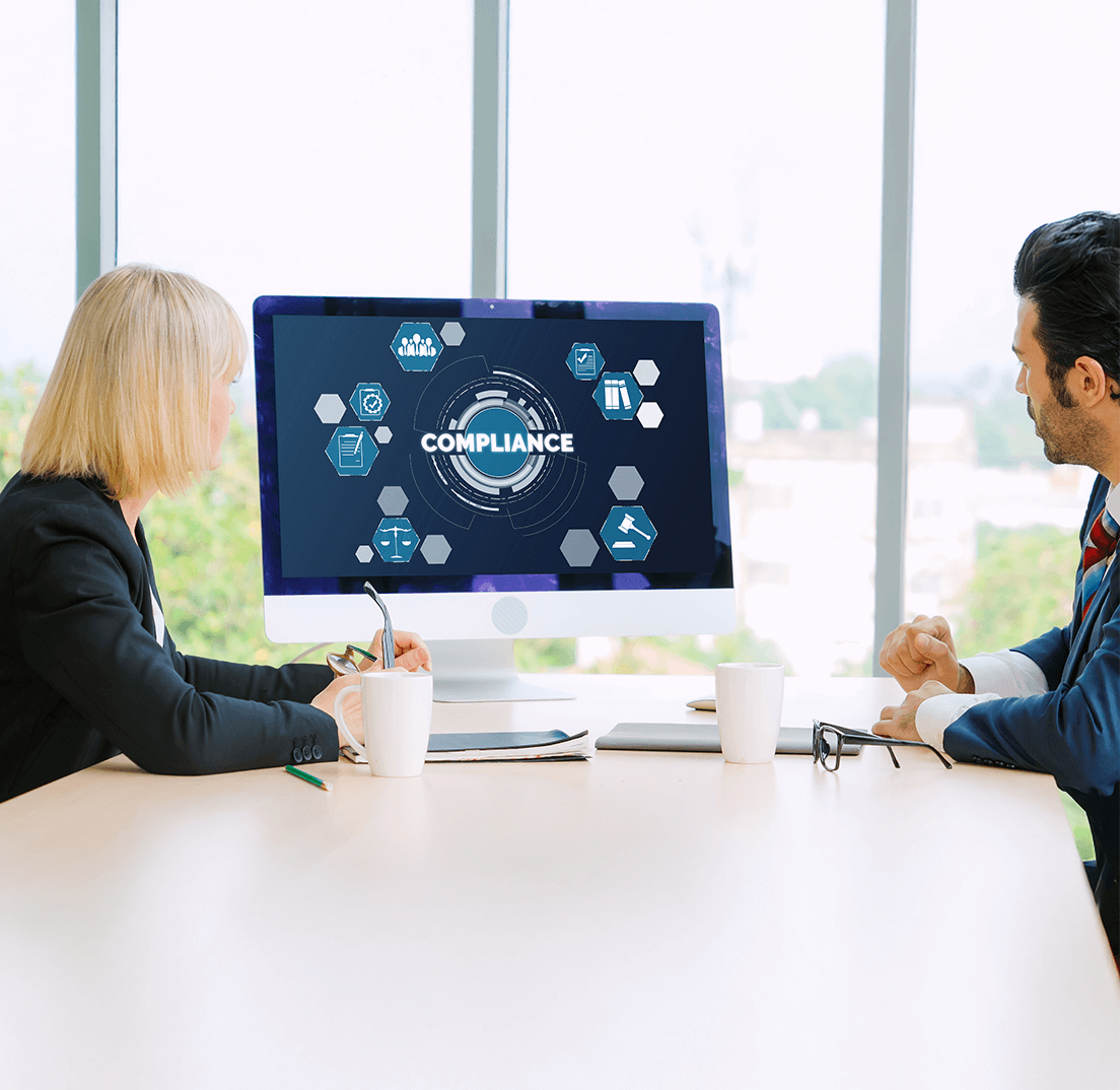 Governance and compliance discussion with professionals reviewing security and audit controls on a digital dashboard.